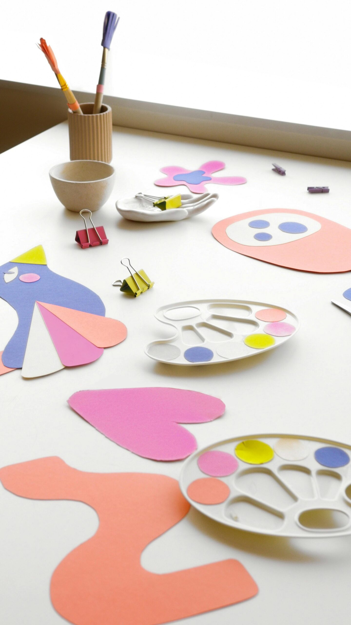 Bright and artistic crafting table with paper shapes and art supplies indoors.