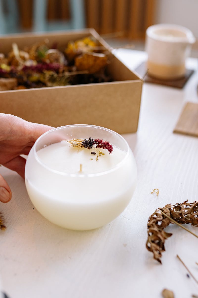 A close-up of a handmade candle adorned with dried flowers, perfect for craft and decor enthusiasts.